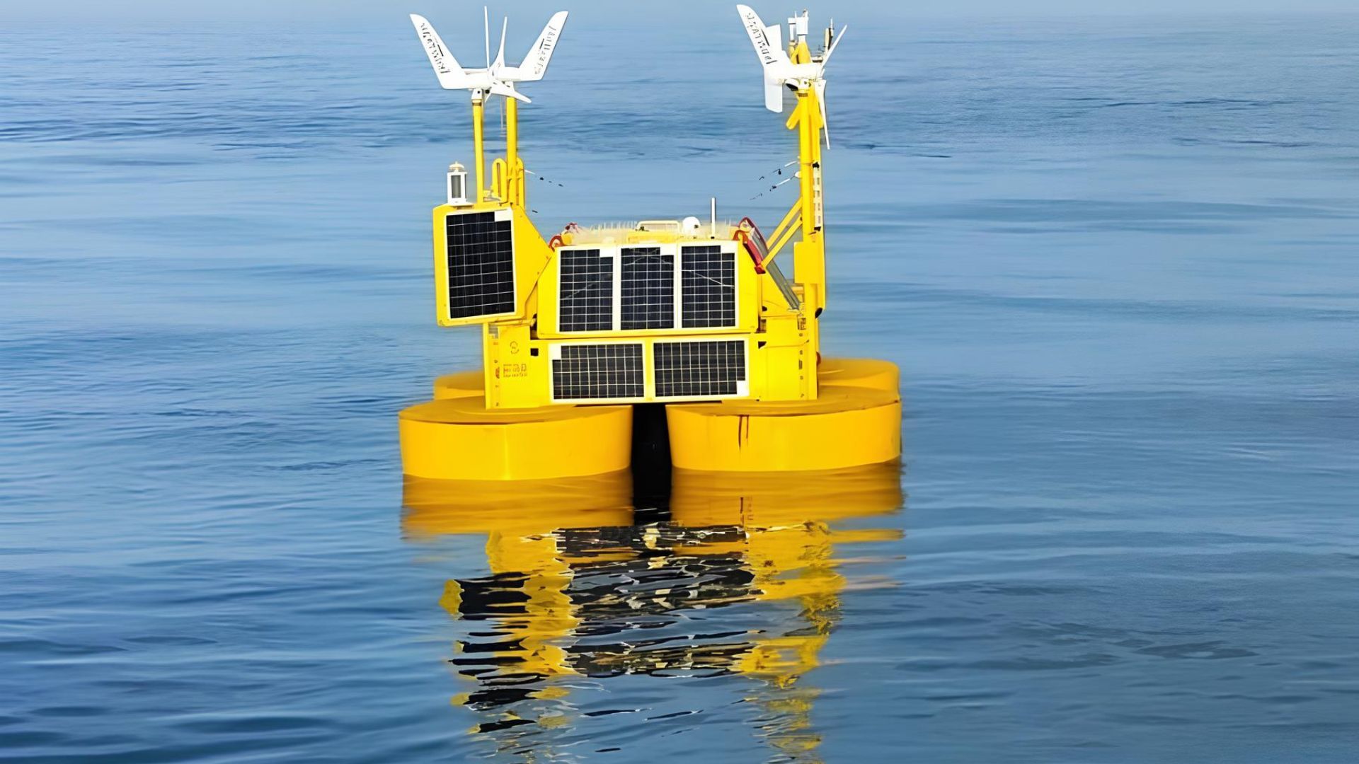 Boia flutuante equipada com painéis solares e turbinas eólicas em operação sobre águas calmas, usada para monitoramento ambiental e coleta de dados meteorológicos.