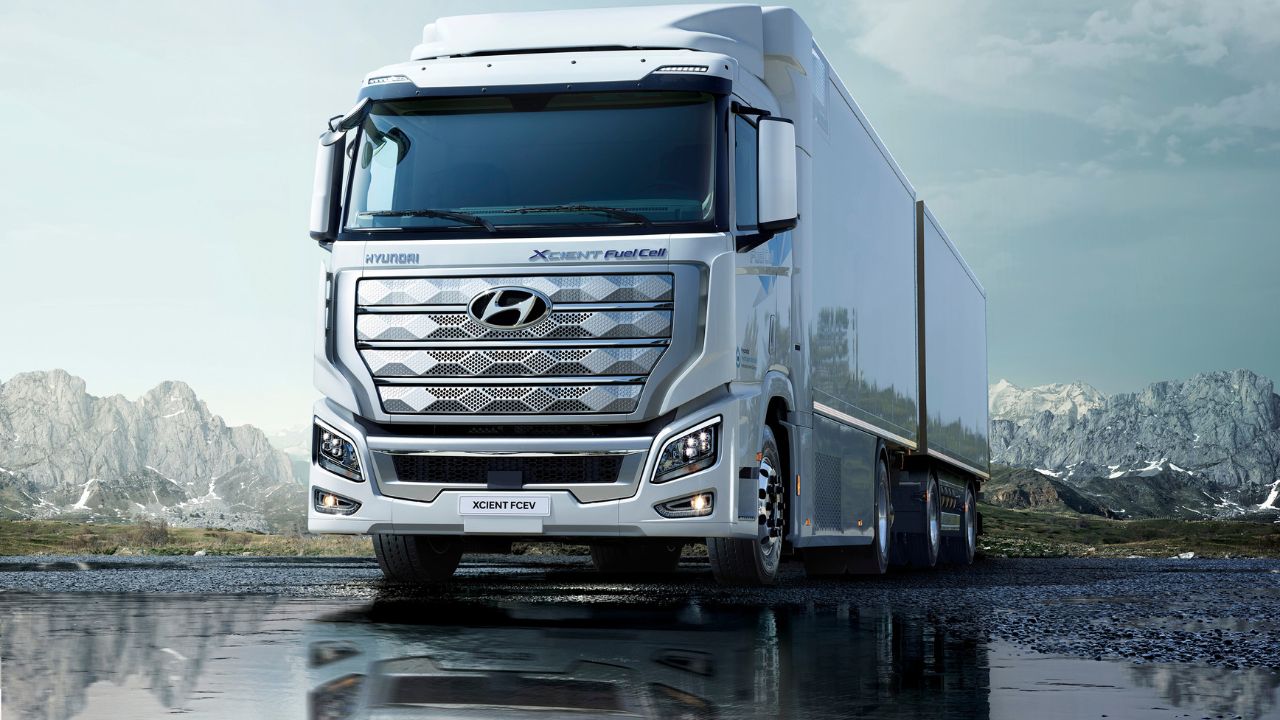 Caminhão Hyundai XCIENT Fuel Cell branco sobre estrada úmida com montanhas ao fundo