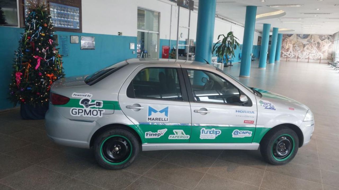 Carro convertido para funcionar com hidrogênio, exibido no hall do Centro de Tecnologia da UFSM, com adesivos do GPMOT e de agências de pesquisa.