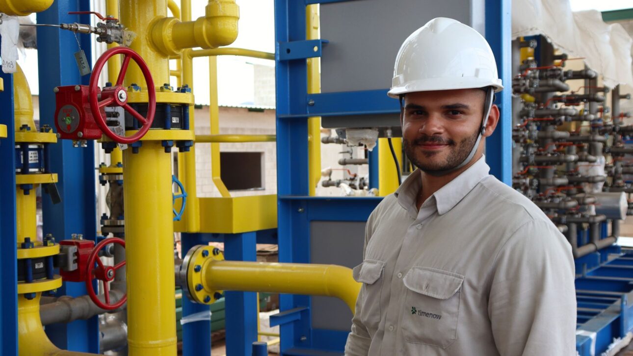 Engenheiro da Timenow em instalação industrial de biogás, ao lado de tubulações e válvulas do sistema de tratamento e distribuição de biometano em projeto de energia renovável.