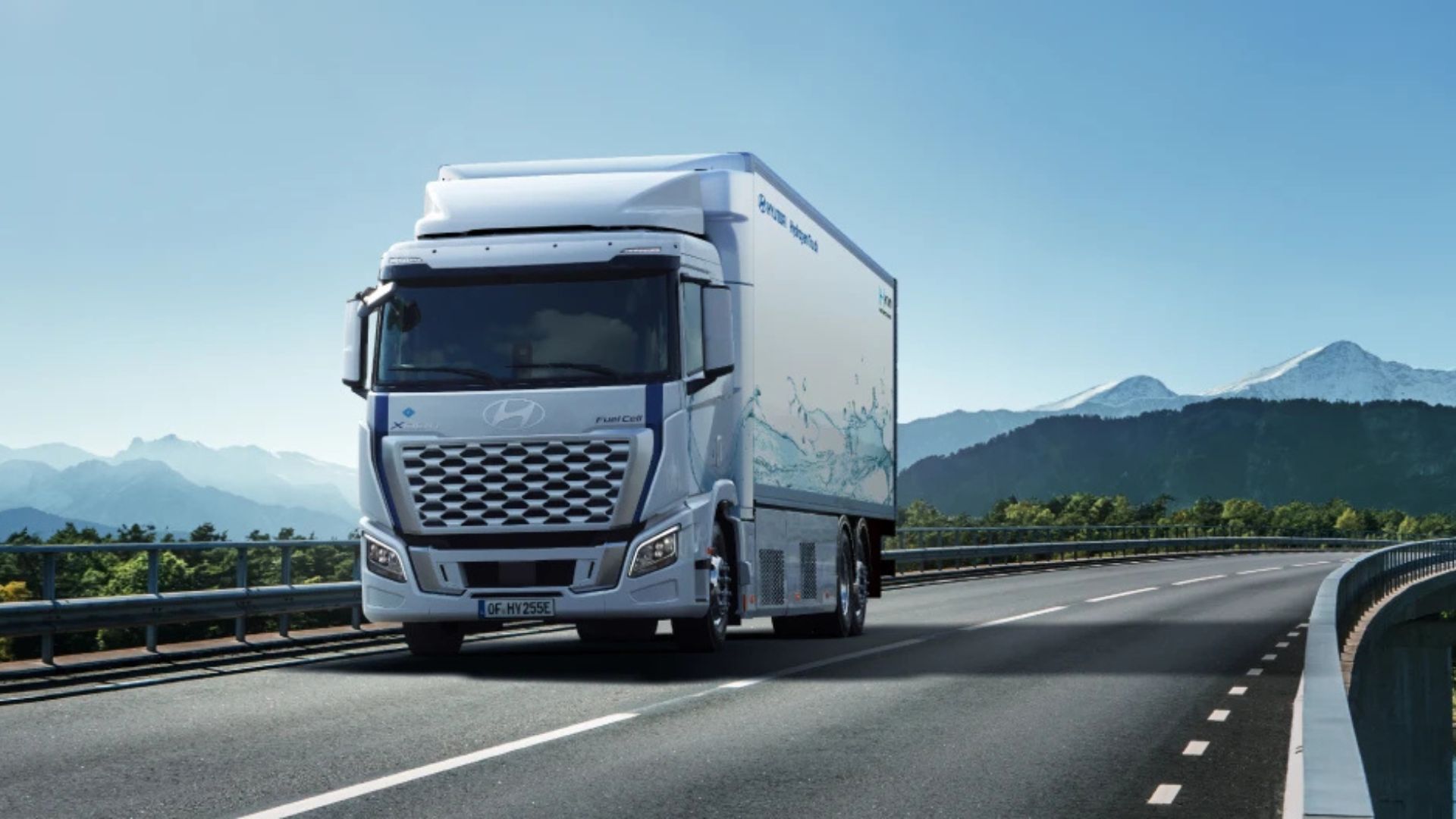 Caminhão Hyundai XCIENT Fuel Cell branco movido a hidrogênio trafegando em rodovia europeia com montanhas ao fundo, representando logística sustentável e transporte limpo.